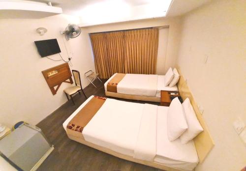 a hotel room with two beds and a television at Hotel Ornate in Dhaka