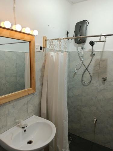 a bathroom with a sink and a shower with a mirror at French garden Pragash Beach Hotel in Trincomalee