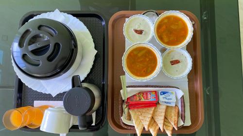 una caja de almuerzo con comida, sopa y pan en Munnar BnB en Munnar