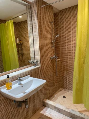 La salle de bains est pourvue d'un lavabo et d'une douche avec un miroir. dans l'établissement Comme à la maison 2, à Derroua