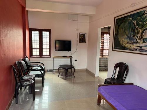 KRK ROOMS Kottarakara في Kottārakara: غرفة معيشة مع كراسي وطاولة وتلفزيون
