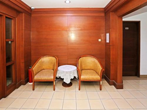 2 chaises et une table blanche dans une pièce dans l'établissement Super OYO Collection O 91898 Series Hotel Kuningan, à Jakarta