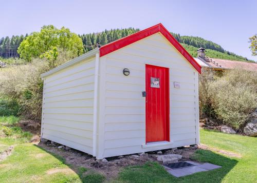 a white and red shed with a red door at Mount Cook Station Shearers Quarters Lodge in Lake Tekapo