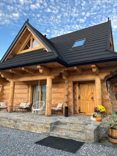 a log cabin with a wooden door and a patio at Pod Brzegiem - Domki góralskie in Czarny Dunajec