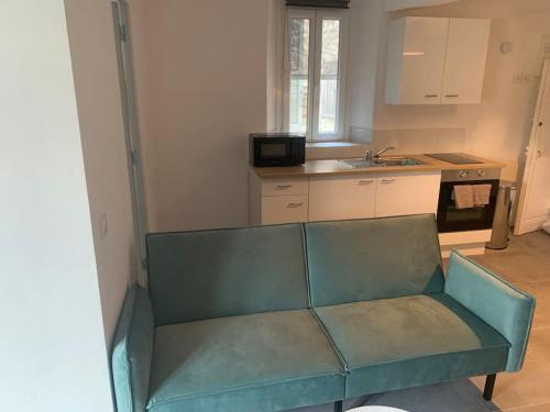 a green couch in a kitchen with a sink at Greolières: Superbe Studio avec vue montagne in Gréolières