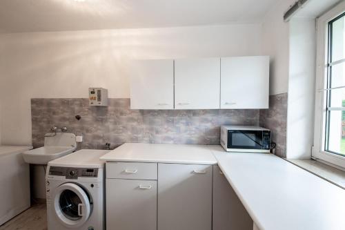 a white kitchen with a washing machine and a sink at Chalet Gletschermoos - Summer Card included in Zell am See