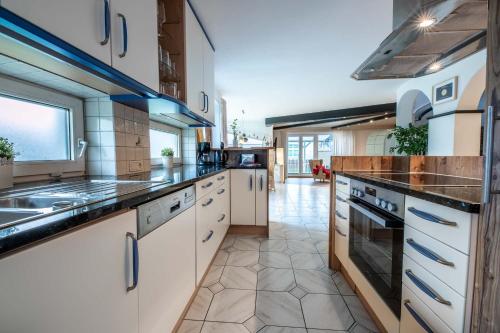 a large kitchen with white cabinets and counters at Chalet Gletschermoos - Summer Card included in Zell am See