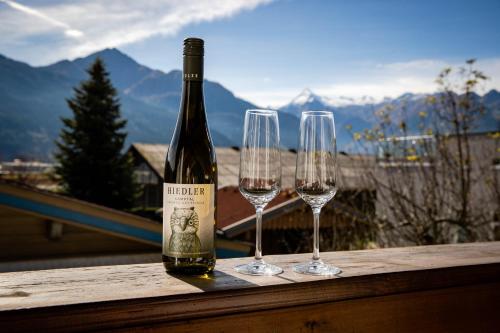 a bottle of wine and two wine glasses on a table at Chalet Gletschermoos - Summer Card included in Zell am See