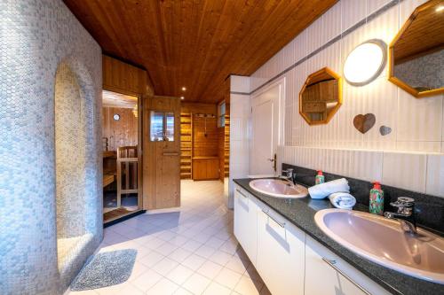 a bathroom with two sinks and a wooden ceiling at Chalet Gletschermoos - Summer Card included in Zell am See