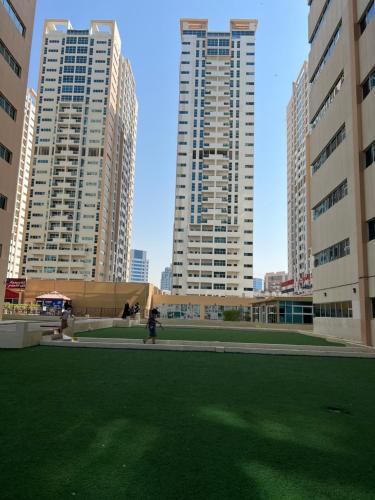 two tall buildings in a city with a grass field at Reem 1 in Ajman 