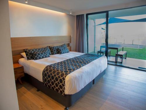 a bedroom with a bed and a balcony with a table at Ocean Front Motel in The Entrance