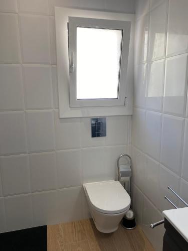 a white bathroom with a toilet and a window at El Mirador de Llançà in Llança