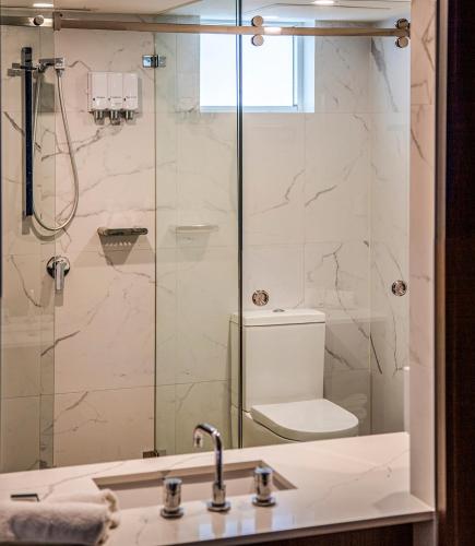 a bathroom with a shower with a toilet and a sink at Ocean Front Motel in The Entrance