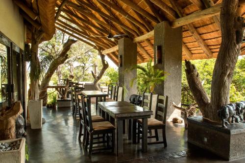 un restaurante con mesas y sillas bajo un techo de madera en Ezulwini Game Lodges, en Balule Game Reserve
