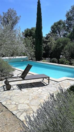 une piscine avec deux chaises longues à côté dans l'établissement le murmure des oliviers, à Castillon-du-Gard