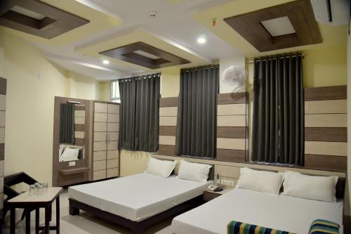 a bedroom with two beds and a table and a chair at Hotel Shri Gourav in Bikaner