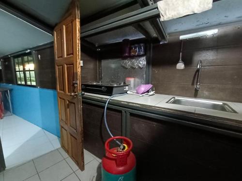 a kitchen with a sink and a fire bucket at Homestay Koperasi Surau Alfalah in Semporna