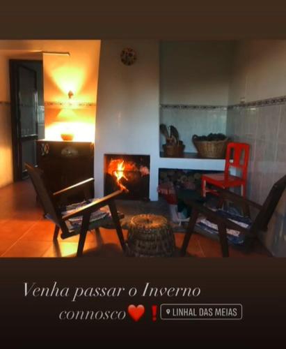 a living room with a fireplace and a table and chairs at Linhal das Meias - São José das Matas in São José