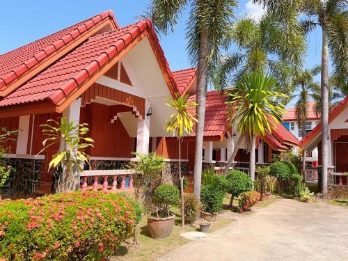 uma casa com telhado vermelho e palmeiras em Bunraksa Resort em Kamphaeng Phet