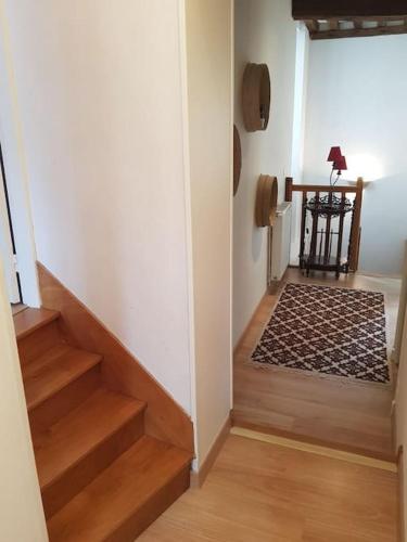 a hallway with stairs leading to a room with a rug at Le petit Conté - Maison calme en centre ville in Sées