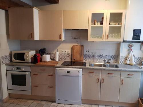 eine Küche mit weißen Schränken, einer Spüle und einer Mikrowelle in der Unterkunft Le petit Conté - Maison calme en centre ville in Sées