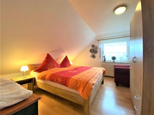 um quarto com uma cama com lençóis vermelhos e uma janela em Haus-Magarethe em Detern