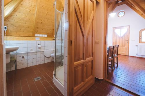 La salle de bains est pourvue d'une douche et d'une porte en verre. dans l'établissement Kormorán Vendégház, à Tiszafüred