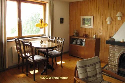 ein Esszimmer mit einem Tisch, Stühlen und einem Kamin in der Unterkunft Haus Hollerbusch in Neunburg vorm Wald