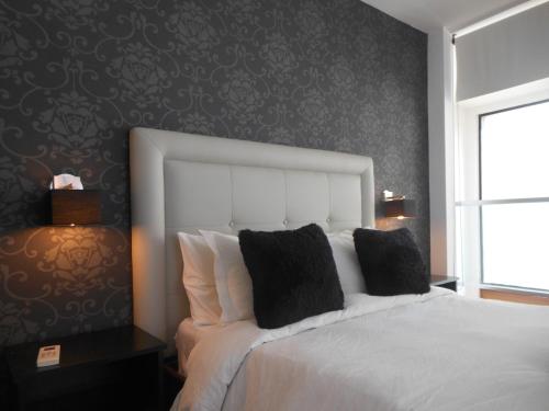 a bedroom with a white bed with a black wall at Calas del Diablo in Punta Del Diablo