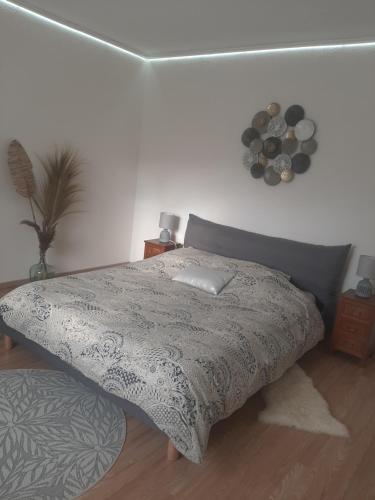 um quarto com uma cama com um edredão cinzento em Gîte à la campagne avec piscine em Biziat