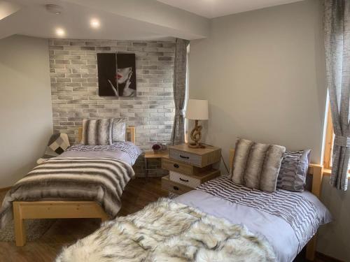 a bedroom with two beds and a brick wall at House Proctor in Stoykite