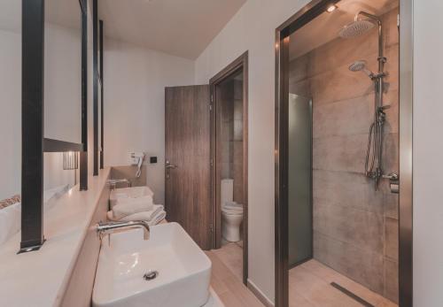 a bathroom with a sink and a shower and a toilet at Cavo di Suites in Kalamaki