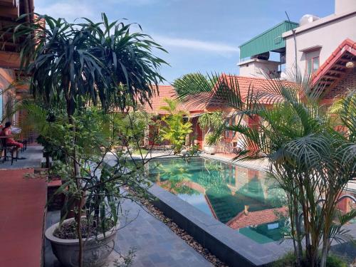 - une piscine bordée de palmiers dans une cour dans l'établissement Tam Coc Tropical Homestay, à Ninh Binh