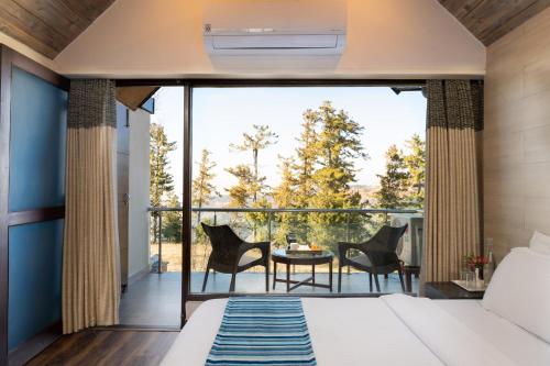 een slaapkamer met een bed en een balkon met een tafel en stoelen bij Koti Resort in Shimla