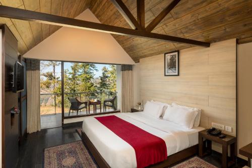 ein Schlafzimmer mit einem großen Bett und einem Balkon in der Unterkunft Koti Resort in Shimla