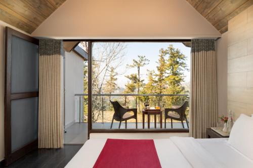ein Schlafzimmer mit Bett und ein Balkon mit Tisch und Stühlen in der Unterkunft Koti Resort in Shimla