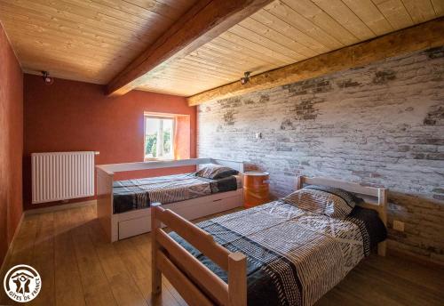 1 dormitorio con 2 camas y pared de ladrillo en LA VIE D'ANCE, en Saint-Anthème
