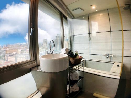 een badkamer met een wastafel, een bad en een raam bij Burgary Hotel in Taipei