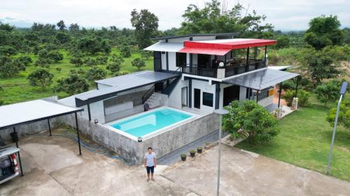 een persoon die voor een huis met een zwembad staat bij ยังคอยที่ดอยนาง พูลวิลล่า in Chiang Dao