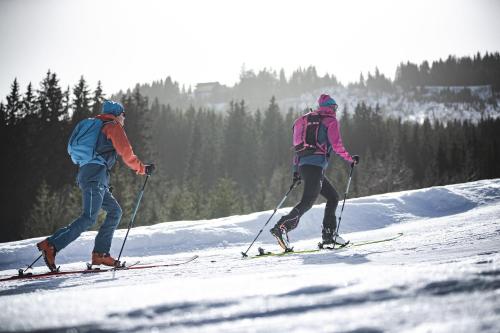 two people are skiing down a snow covered slope at Chalet Gletschermoos - Summer Card included in Zell am See