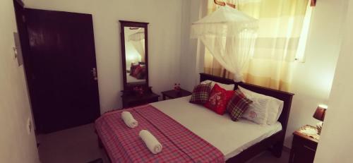 a bedroom with a bed with red pillows and a mirror at Southern Comforts - Galle Fort in Galle
