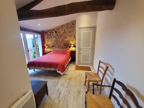 a bedroom with a red bed and a table and chairs at Gites De La Brunière in La Pommeraie-sur-Sèvre