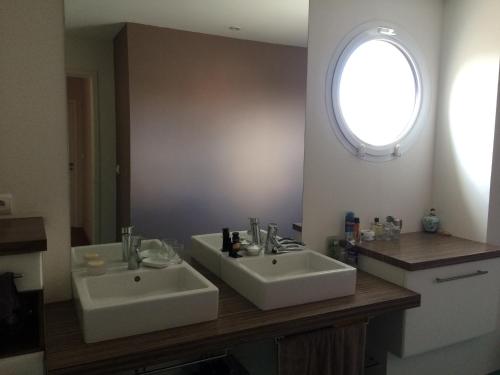 een badkamer met 2 witte wastafels en een raam bij Chambres au calme chez l'habitant in Vertou