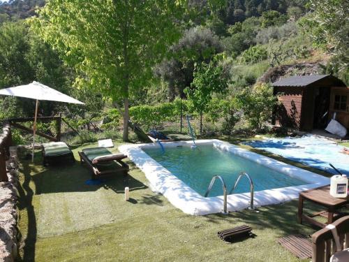 una piscina en un patio con mesa y sombrilla en A 11 km de Riopar Casa Acogedora con sabor antaño, 