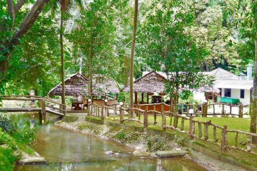 a wooden fence next to a river with houses at The Creek Garden Resort Huainamrin ห้วยนำ้ริน in Mae Hong Son