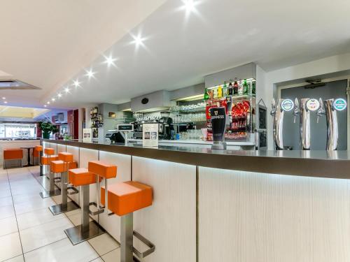 un bar en un restaurante con taburetes naranjas en Hôtel Agena, en Lourdes
