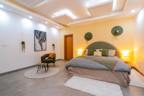 - une chambre avec un grand lit et une chaise dans l'établissement Lighthouse Signature Suites, à Dakar