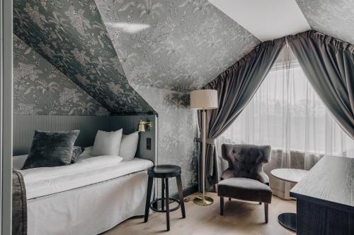 een slaapkamer met een bed, een stoel en een raam bij Skara Stadshotell in Skara