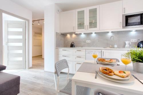 a white kitchen with a table and two glasses of orange juice at Tyzenhauz Apartments Piwna Street in Krakow