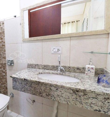 a bathroom with a sink and a mirror and a toilet at Praia com Conforto in Guaratuba